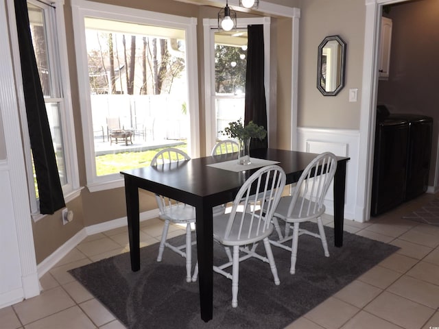 dining space featuring light tile patterned floors, wainscoting, and washer and clothes dryer