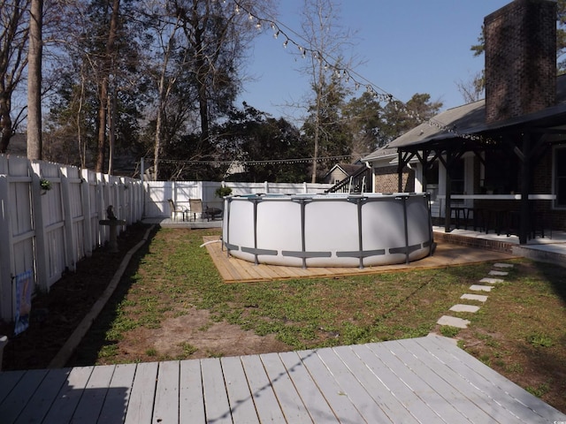 view of yard featuring a deck, a fenced backyard, and a fenced in pool