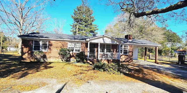 view of front of property with driveway, covered porch, a chimney, a carport, and brick siding