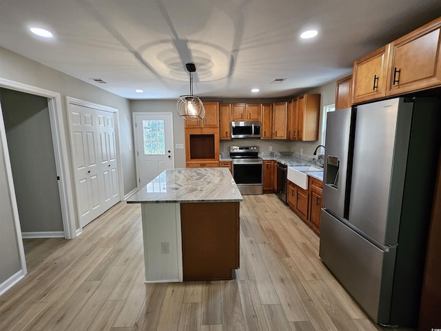 kitchen featuring visible vents, a sink, a center island, light wood-style floors, and appliances with stainless steel finishes