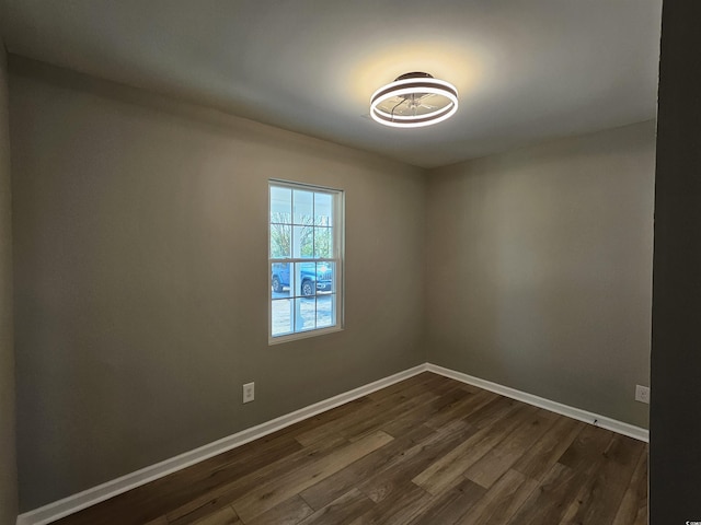 spare room featuring baseboards and dark wood-style flooring