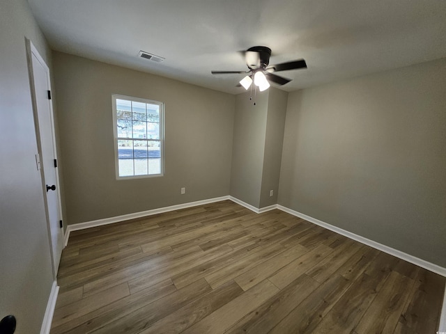 spare room with visible vents, baseboards, a ceiling fan, and dark wood-style flooring