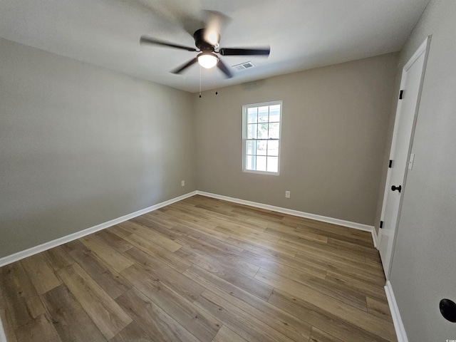 unfurnished room with wood finished floors, a ceiling fan, visible vents, and baseboards