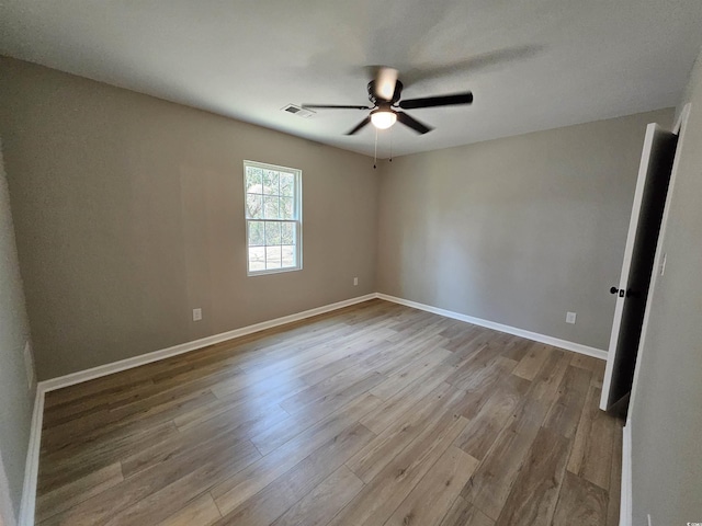 spare room featuring visible vents, baseboards, wood finished floors, and a ceiling fan