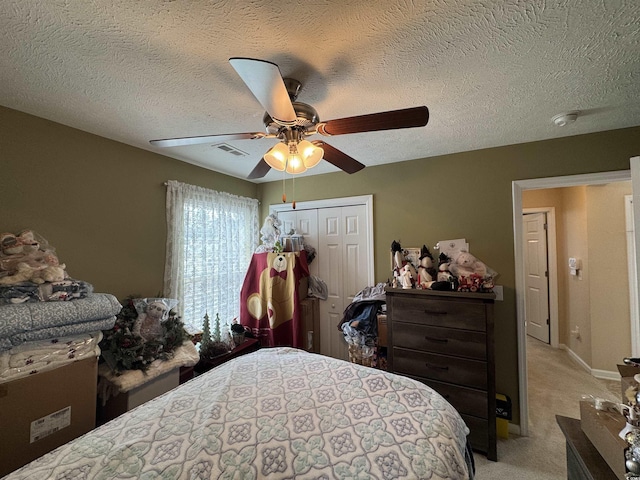 bedroom featuring visible vents, light carpet, a ceiling fan, a textured ceiling, and a closet