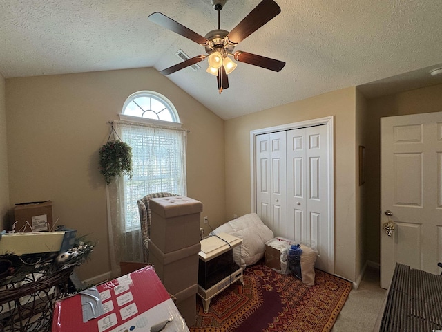 bedroom featuring a ceiling fan, carpet, vaulted ceiling, a closet, and a textured ceiling