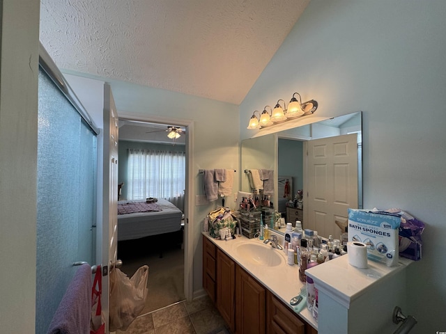 bathroom with a textured ceiling, connected bathroom, lofted ceiling, ceiling fan, and vanity