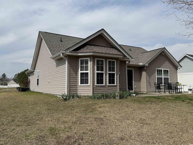 view of front of home with a front lawn, a patio area, and roof with shingles