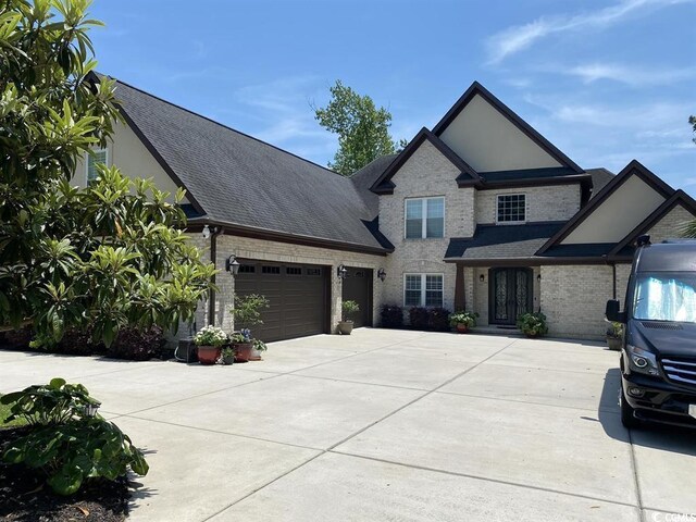view of front of home featuring driveway, a shingled roof, an attached garage, and brick siding