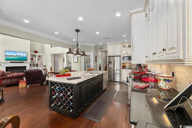 9785 Anchor Dr, Longs, SC 29568 - kitchen featuring appliances with stainless steel finishes, a sink, crown molding, light stone countertops, and a kitchen island with sink