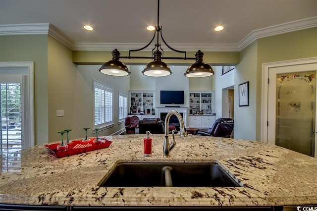 9785 Anchor Dr, Longs, SC 29568 - kitchen featuring a sink, open floor plan, crown molding, light stone counters, and a fireplace