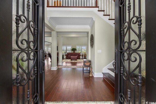 entryway featuring dark wood finished floors, baseboards, ornamental molding, and stairway
