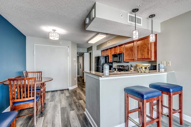 5300 N Ocean Blvd Unit 1003, Myrtle Beach, SC 29577 - kitchen featuring visible vents, dark wood-type flooring, black appliances, a peninsula, and brown cabinetry