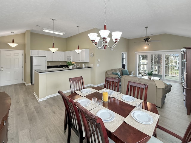 dining room featuring baseboards, light wood-type flooring, vaulted ceiling, ceiling fan with notable chandelier, and a textured ceiling