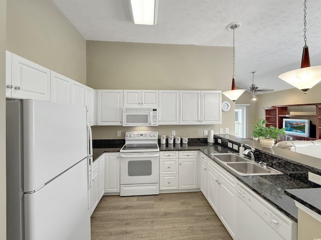 kitchen featuring a sink, dark countertops, white appliances, and lofted ceiling