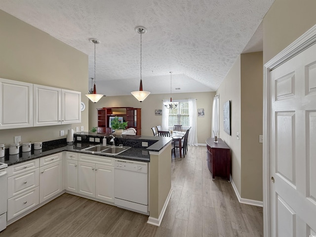 kitchen with light wood finished floors, lofted ceiling, a peninsula, white appliances, and a sink