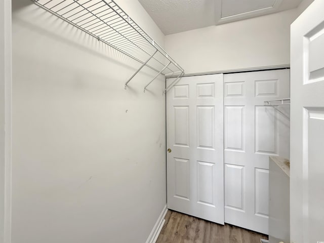 walk in closet with wood finished floors