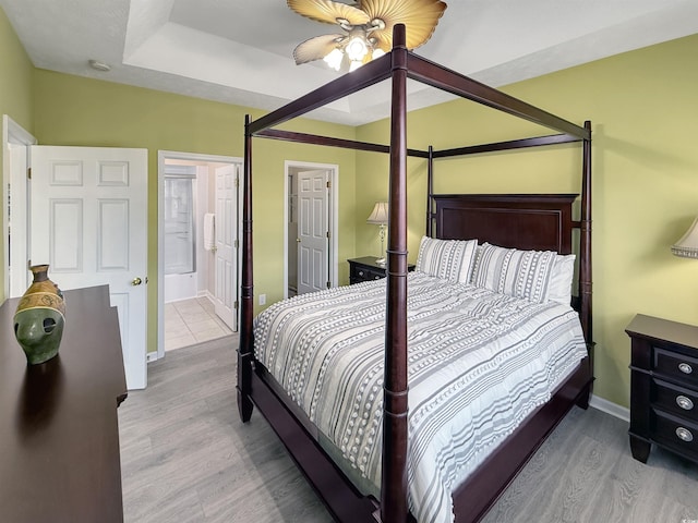 bedroom featuring a ceiling fan, wood finished floors, baseboards, and ensuite bathroom