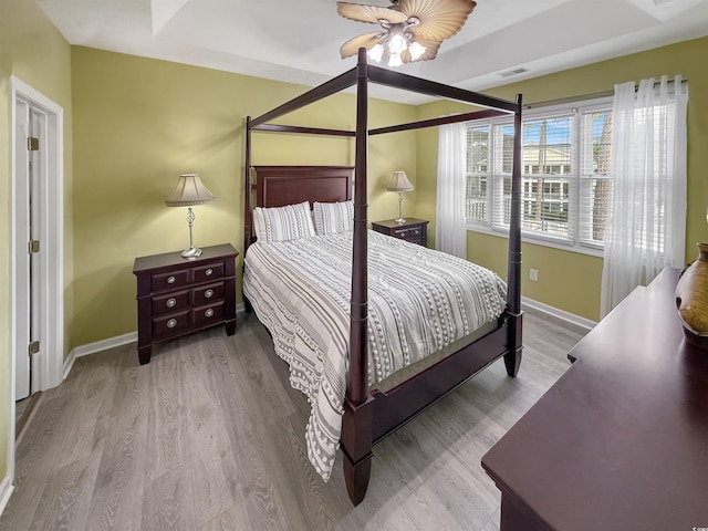 bedroom with a ceiling fan, baseboards, visible vents, and wood finished floors