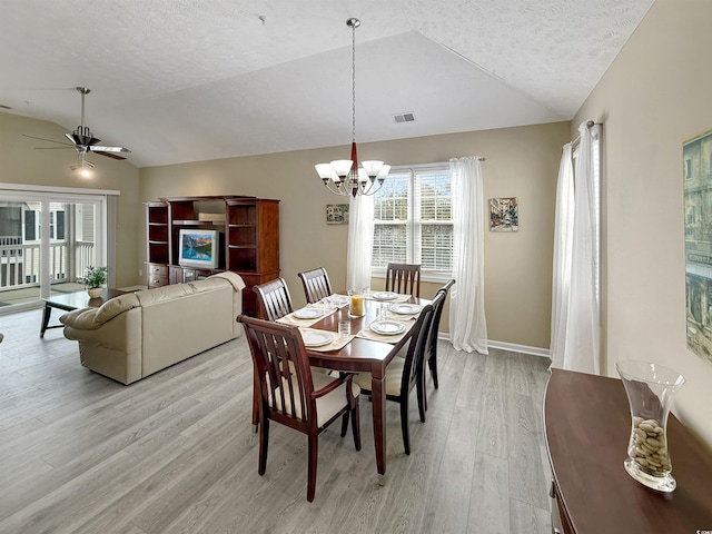 dining area with lofted ceiling, light wood-style flooring, ceiling fan with notable chandelier, and visible vents