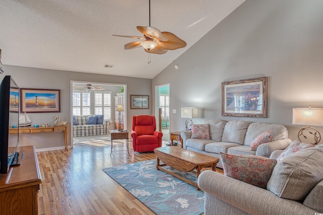 living room with visible vents, high vaulted ceiling, light wood-style flooring, a textured ceiling, and ceiling fan