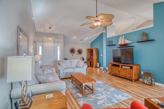 living room featuring lofted ceiling, wood finished floors, baseboards, and ceiling fan