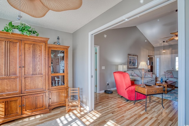 interior space with vaulted ceiling, a ceiling fan, baseboards, and light wood finished floors