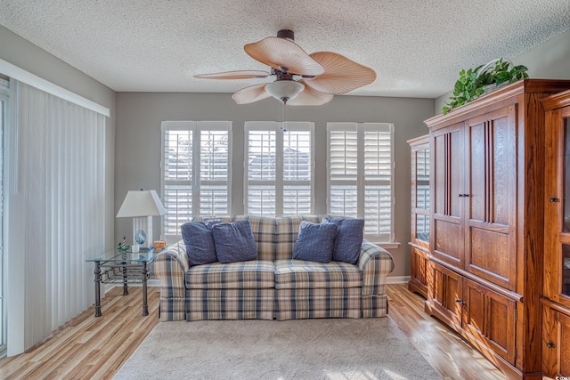 interior space featuring light wood-style flooring, a textured ceiling, and ceiling fan