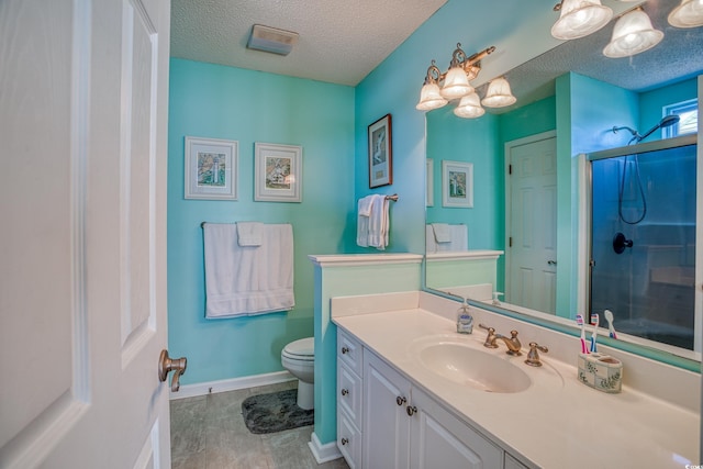 bathroom featuring toilet, a stall shower, a textured ceiling, baseboards, and vanity