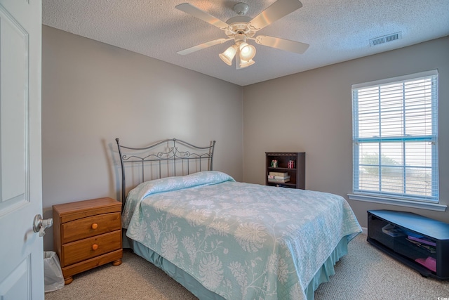 bedroom with light carpet, visible vents, a textured ceiling, and ceiling fan