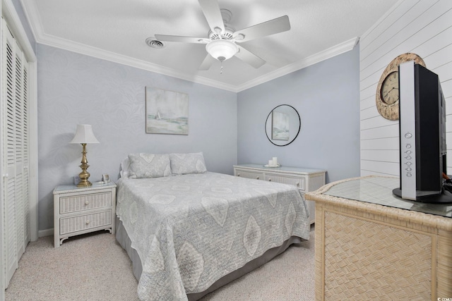 bedroom featuring visible vents, ornamental molding, a ceiling fan, a closet, and light colored carpet