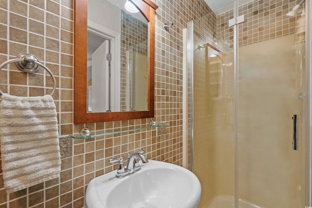 bathroom with a sink, tasteful backsplash, tile walls, and a shower stall