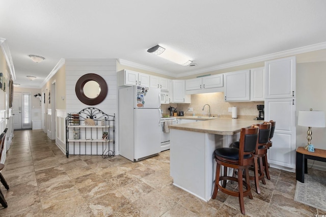 kitchen featuring light countertops, a kitchen breakfast bar, a peninsula, white appliances, and a sink