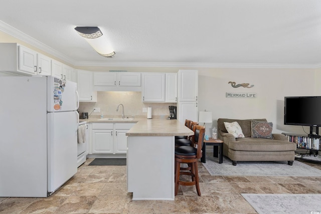 kitchen featuring a breakfast bar, a peninsula, freestanding refrigerator, light countertops, and white cabinetry