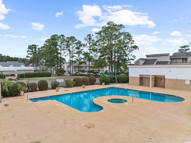 pool with a patio area and a hot tub