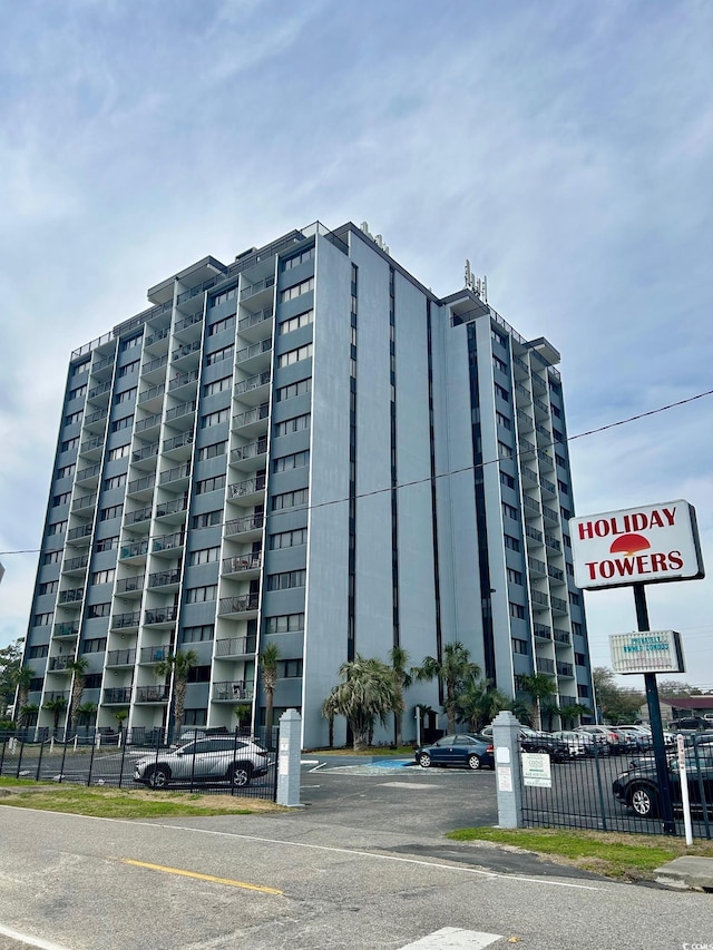 view of building exterior with uncovered parking and fence