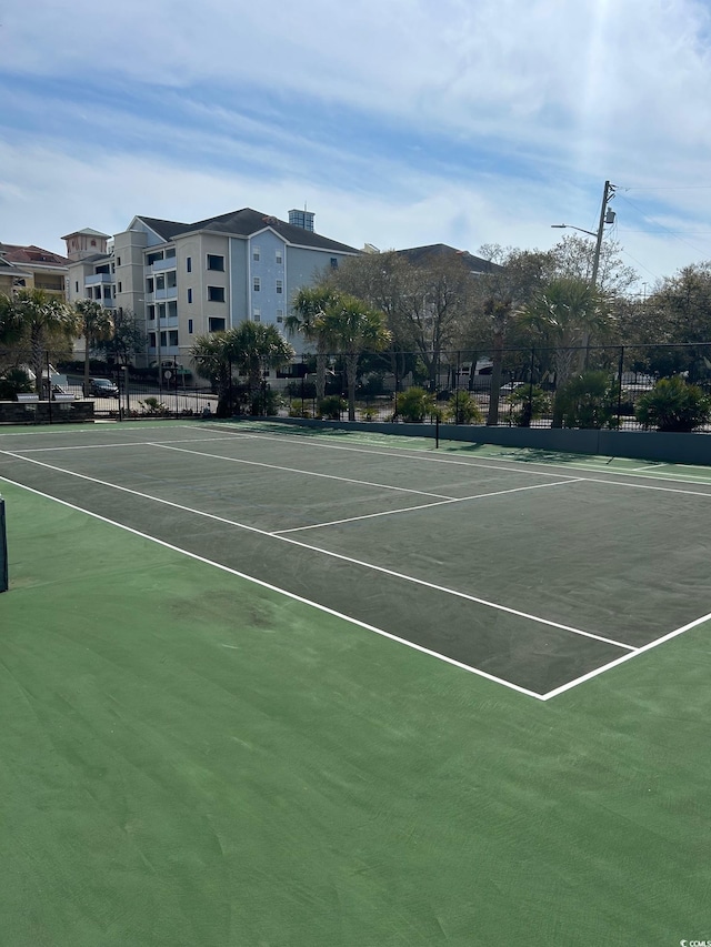 view of tennis court with community basketball court and fence