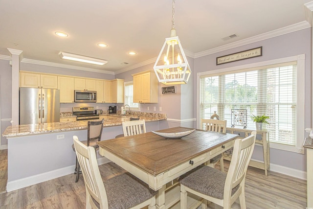 dining room with plenty of natural light, light wood-style floors, visible vents, and ornamental molding