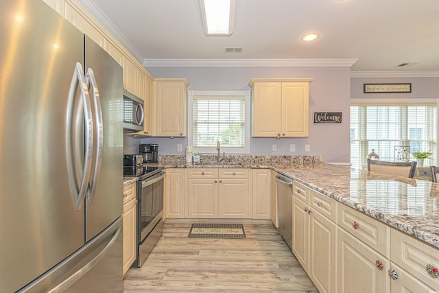 kitchen with visible vents, crown molding, light wood-type flooring, light stone counters, and appliances with stainless steel finishes