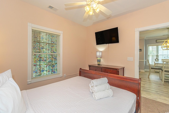 bedroom with visible vents, wood finished floors, and ceiling fan with notable chandelier