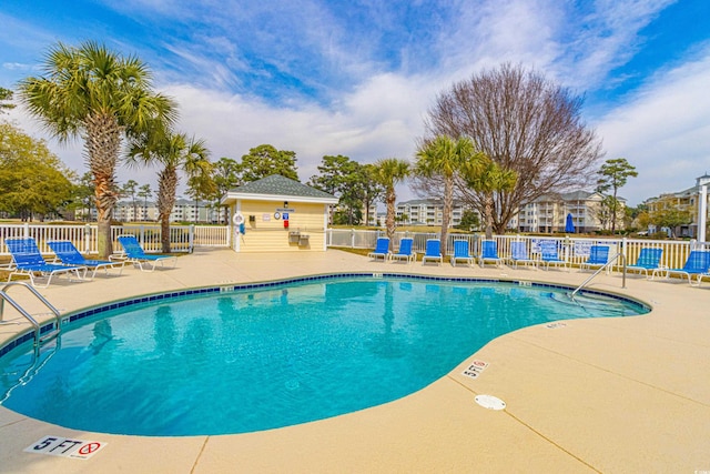 community pool with a patio and fence