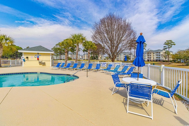 community pool with a patio area and fence