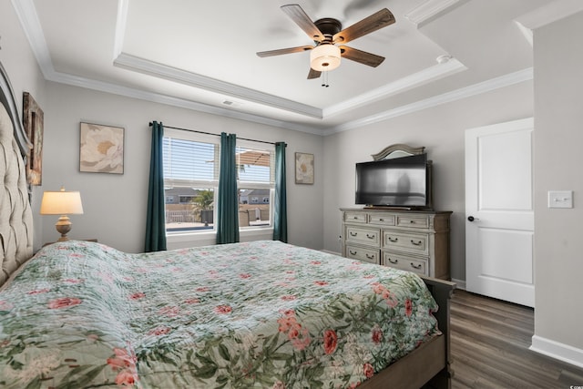 bedroom featuring a raised ceiling, dark wood-style floors, and ornamental molding