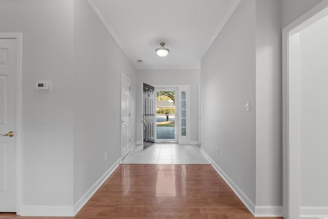 hall with crown molding, baseboards, and light wood-type flooring