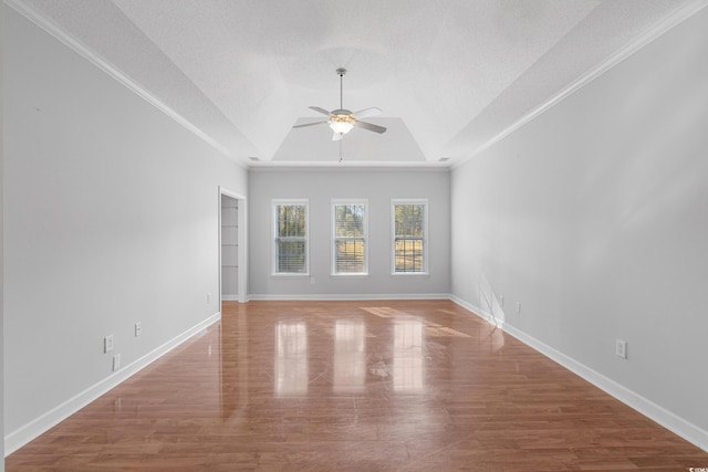 spare room with a raised ceiling, a textured ceiling, wood finished floors, baseboards, and ceiling fan