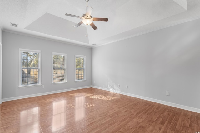 unfurnished room featuring a tray ceiling, visible vents, and baseboards