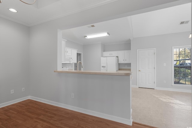 kitchen featuring visible vents, white appliances, a peninsula, light countertops, and baseboards