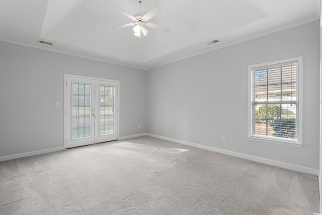 empty room with a raised ceiling, visible vents, and light carpet