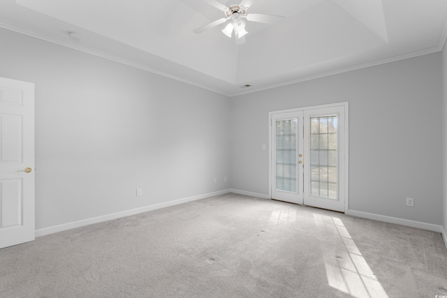 carpeted spare room featuring baseboards, ceiling fan, french doors, crown molding, and a raised ceiling