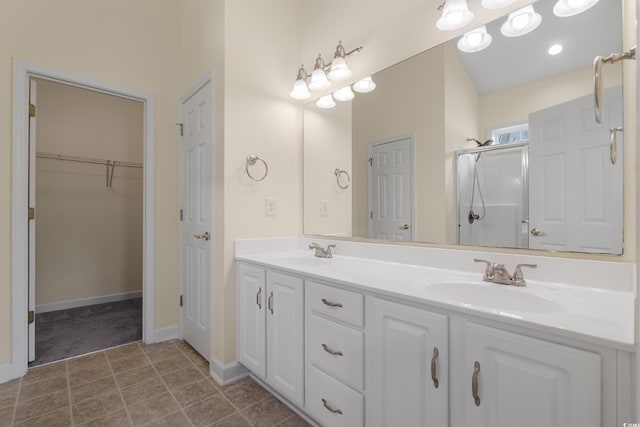 full bathroom featuring a sink, double vanity, a shower stall, and tile patterned floors